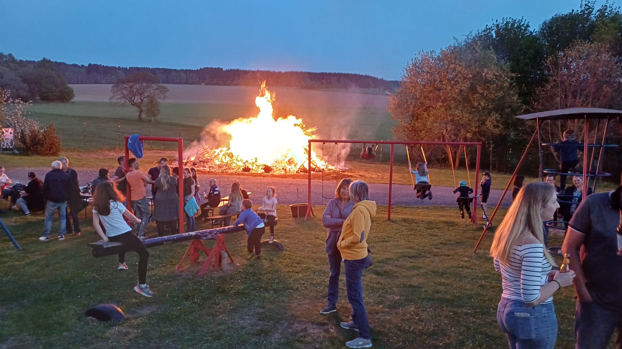 Brennendes Hexenfeuer neben Spielplatz mit Personen
